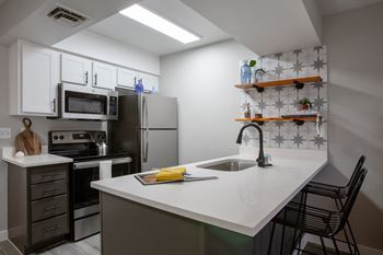 A kitchen with a white counter top and stainless steel appliances